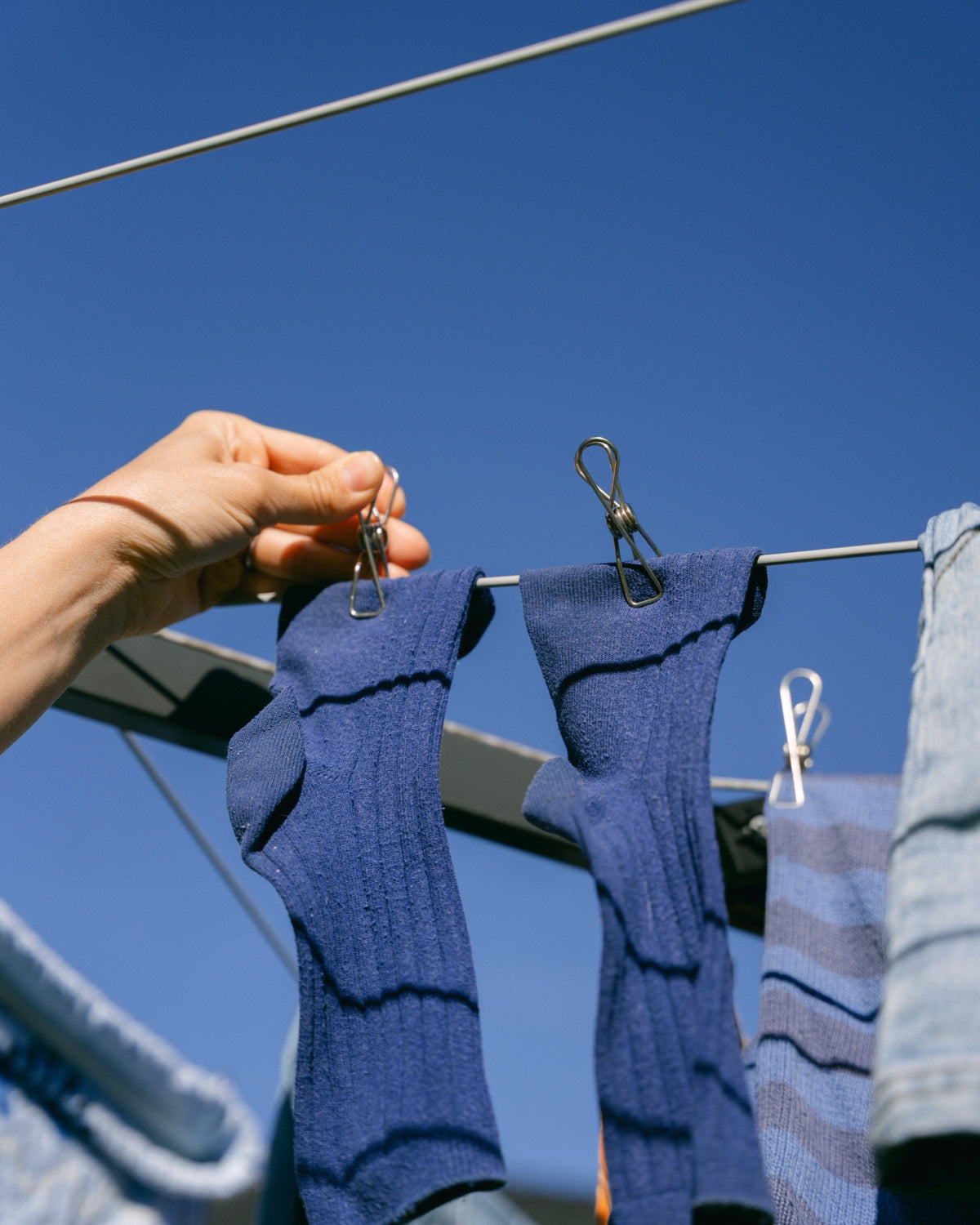 Pegging blue socks to a rotary clothesline with Forever Pegs