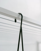 Hang Easy Basket Hanger hooked over the metal bar of a folding clothesline