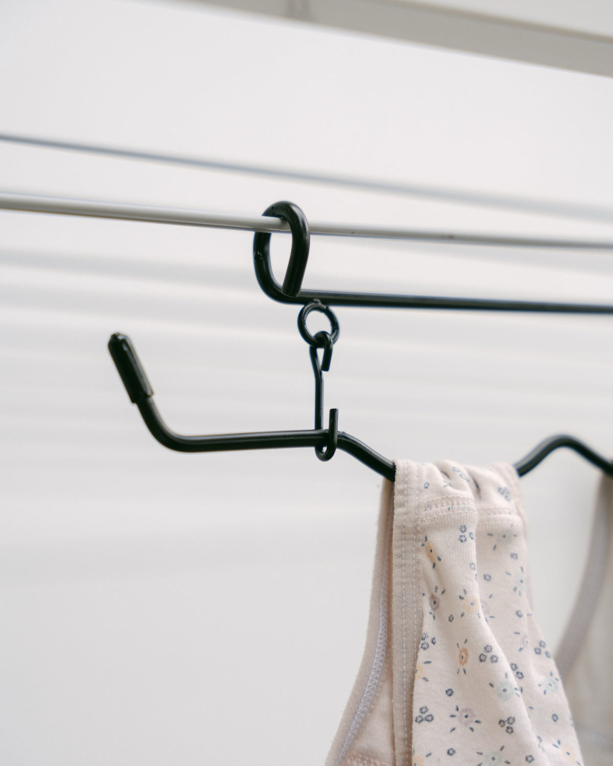 Close-up of The Undie Hanger hook and wave-shaped rail holding a baby onesie