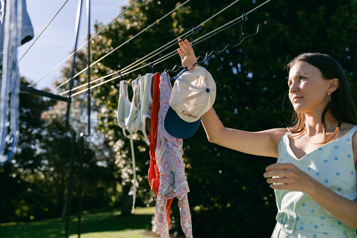 Woman adding to a fully loaded Undie Hanger on a sunny rotary clothesline